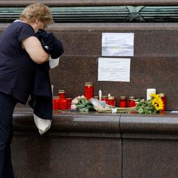 Eine Frau steht vor dem Gesundheitsministerium in Wien vor Blumen und Kerzen.