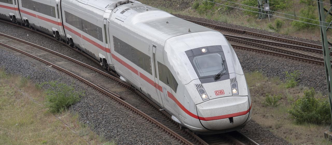 A Deutsche Bahn ICE train travels through a landscape.