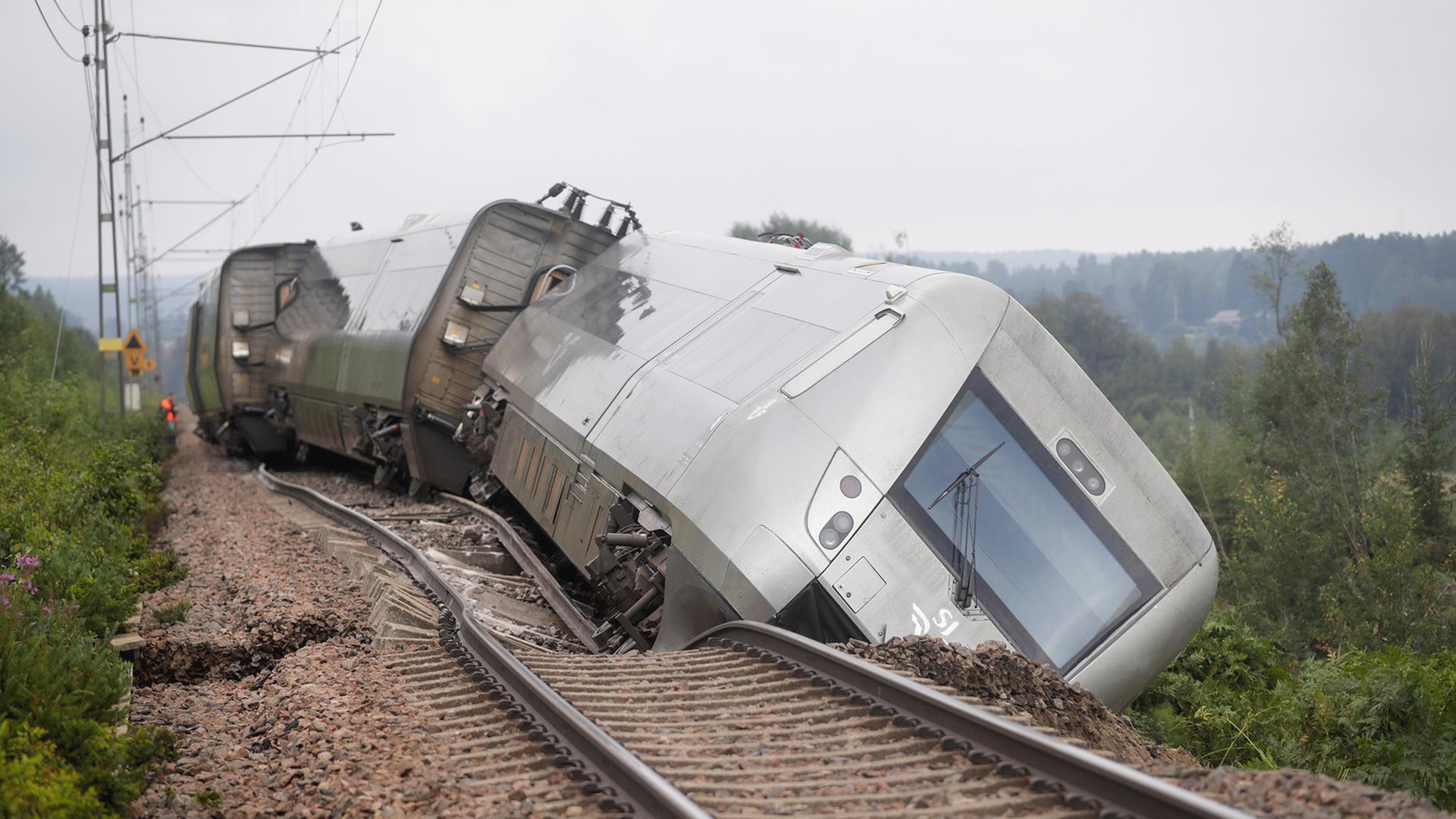 Ein entgleister Personenzug liegt neben den Schienen.
