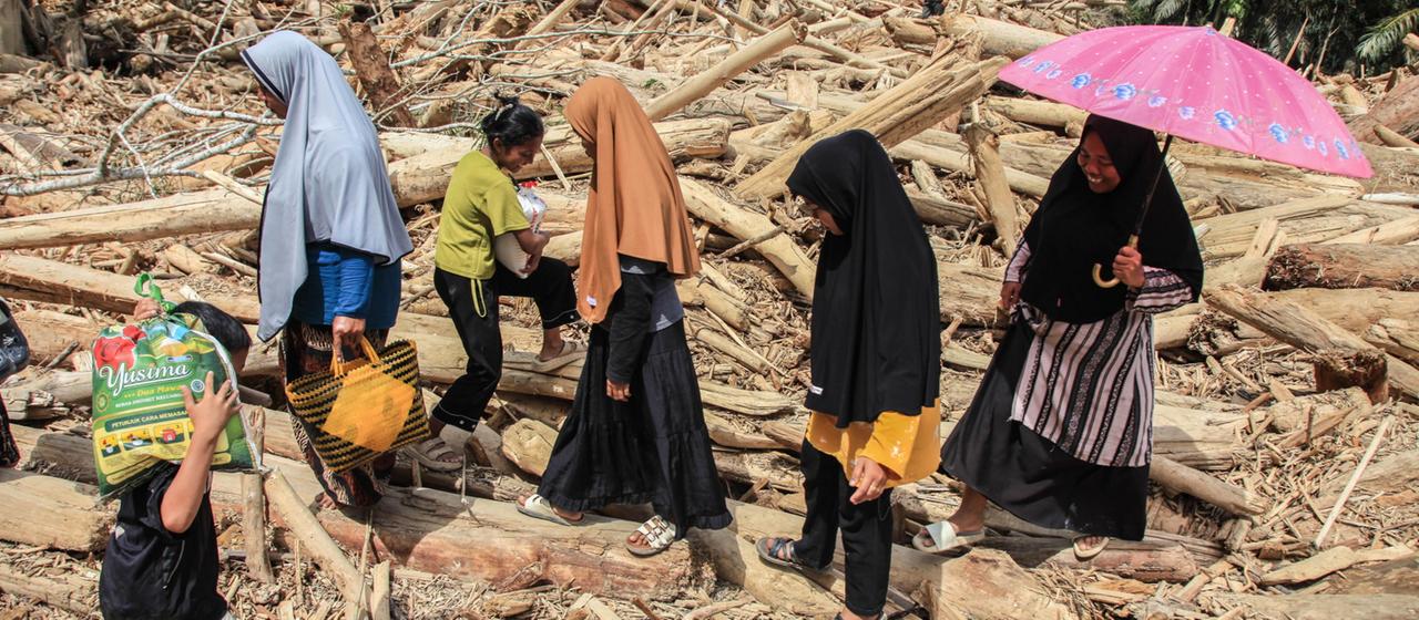 Menschen gehen über Trümmer in der von Fluten zerstörten Provinz Aceh in Indonesien.