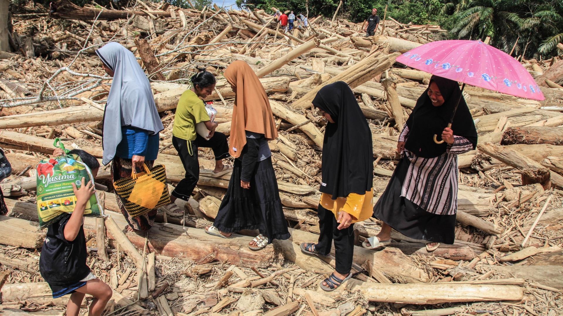Menschen gehen ber Trmmer in der von Fluten zerstrten Provinz Aceh in Indonesien. | EPA