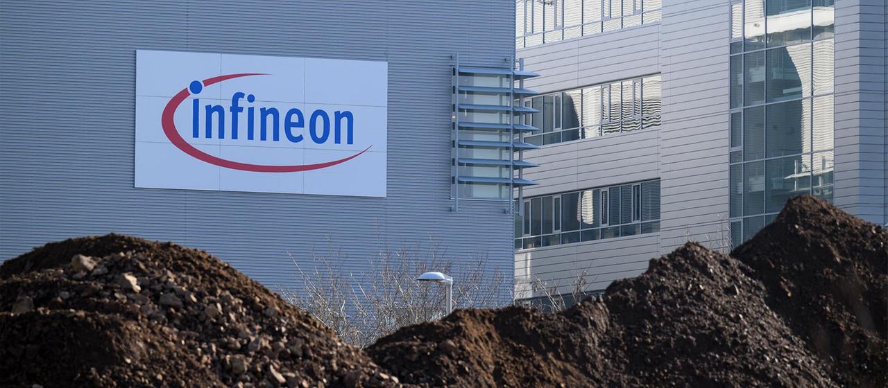 Firmengebäude von Infineon, hinter Erdhaufen auf der Fläche für ein neues Werk.