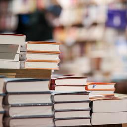 Bücher liegen gestapelt auf einem Tisch.