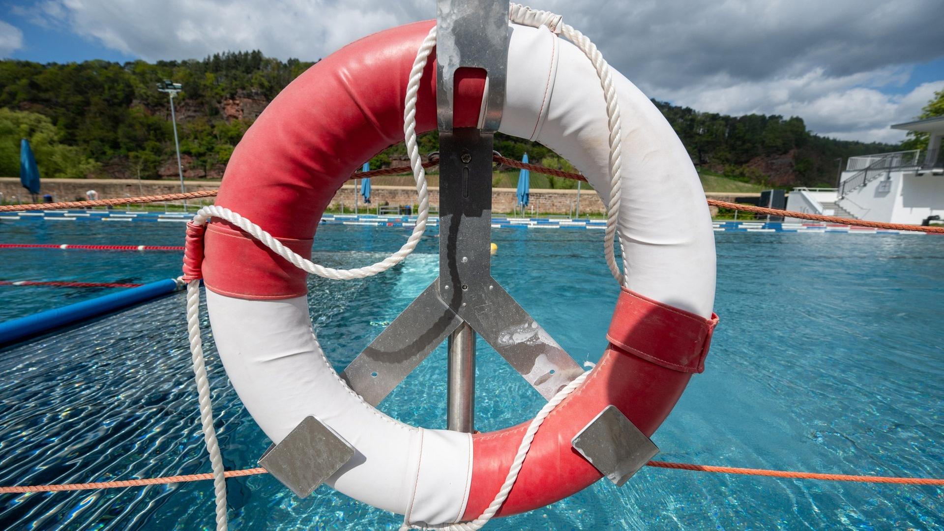 Ein Rettungsreifen hängt auf einem Geländer, vor einem Schwimmbecken. | dpa Bildfunk, Harald Tittel