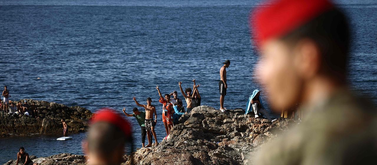 Angehörige der spanischen Armee beobachten eine Gruppe von Migranten nahe dem Grenzübergang der spanischen Exklave Ceuta.