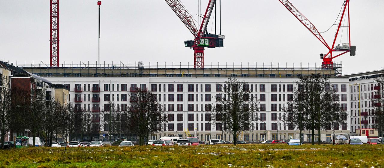 Mehrere Baukräne stehen über einem im Bau befindlichen Wohngebäude in Berlin