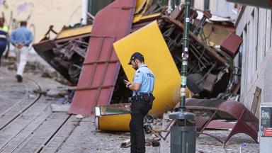 Ein Polizist steht vor den Wrackteilen einer verunglückten Standseilbahn in Lissabon.