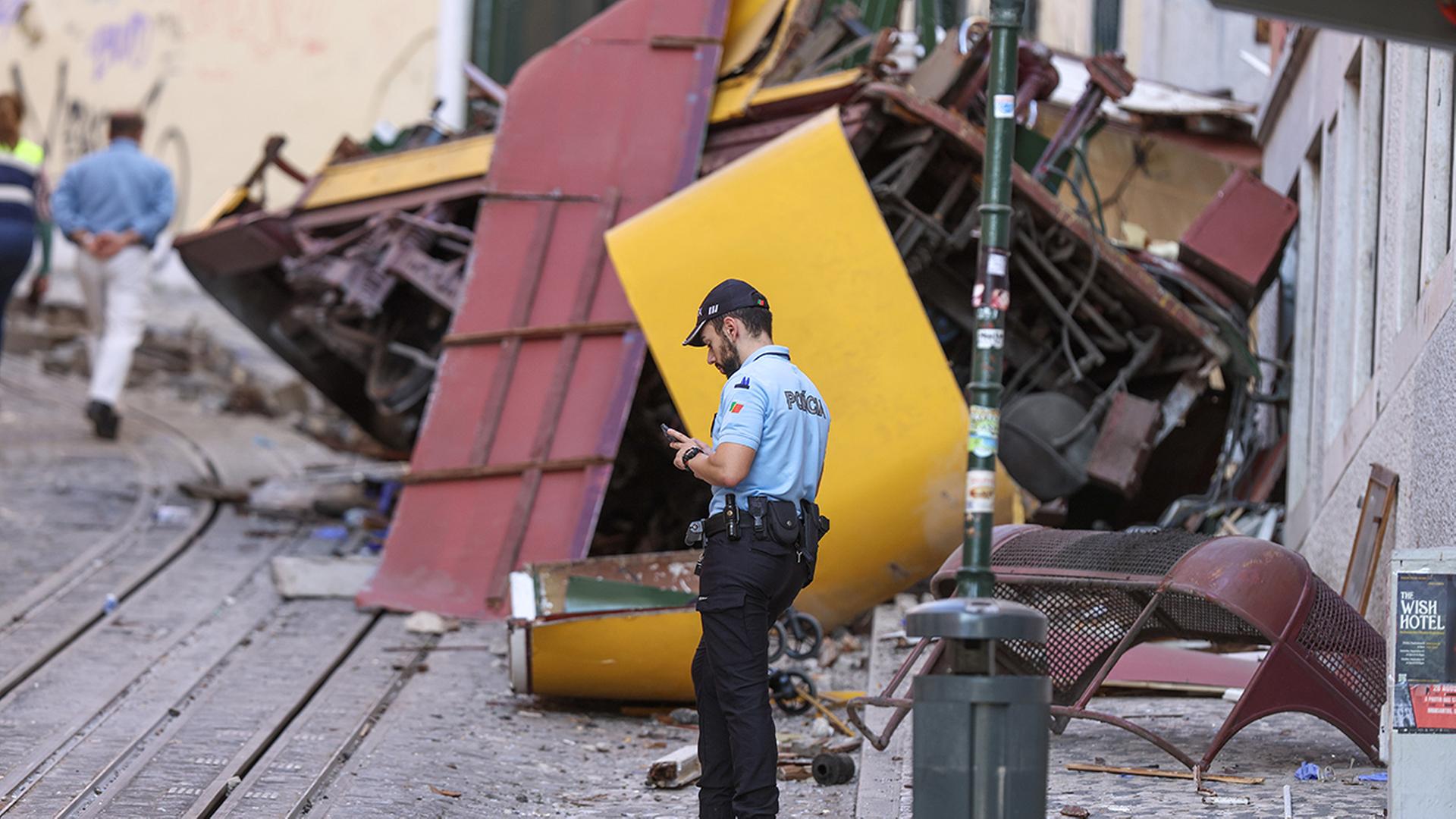 Ein Polizist steht vor den Wrackteilen einer verunglückten Standseilbahn in Lissabon. | EPA