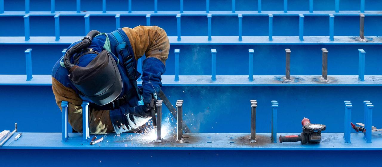 Ein Arbeiter führt Schweißarbeiten an einer großen Stahlkonstruktion aus.