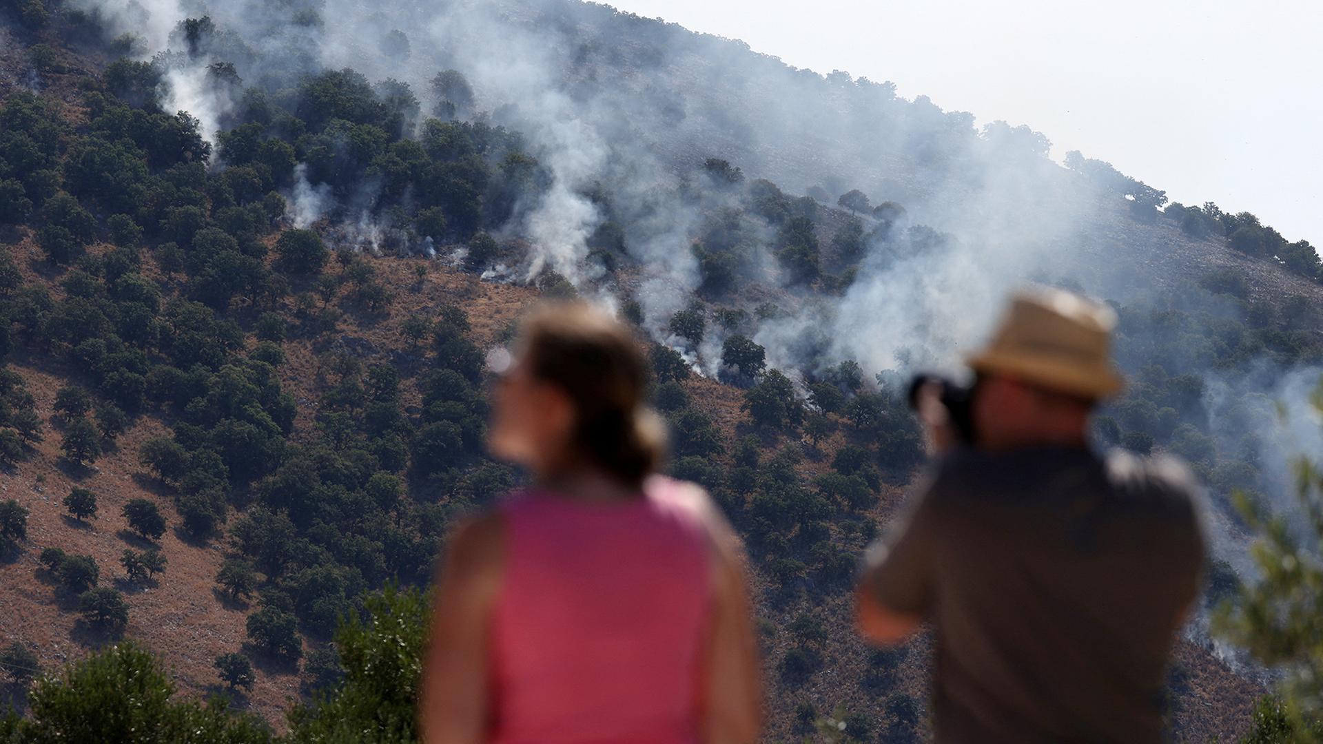 Touristen beobachten, wie Rauch während eines Waldbrandes in Albanien aufsteigt.  | REUTERS