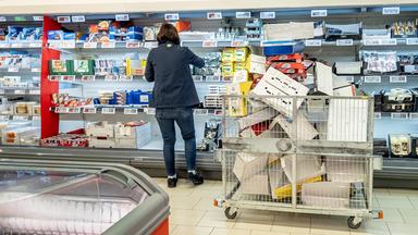 Eine Supermarkt-Mitarbeiterin räumt Waren in ein Kühlregal.