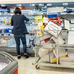 Eine Supermarkt-Mitarbeiterin räumt Waren in ein Kühlregal.