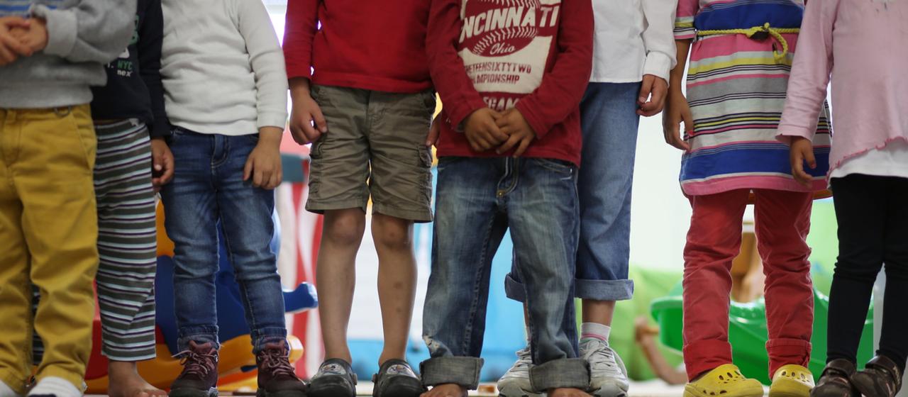 Kinder stehen in einer Kita nebeneinander.