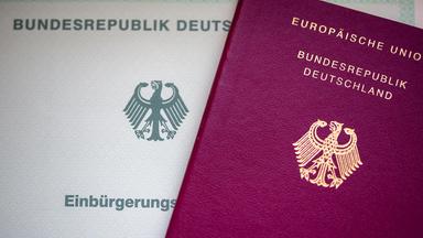 Eine Einbürgerungsurkunde liegt neben einem Reisepass