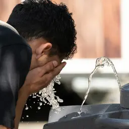  Ein Mann erfrischt sich bei heißem Sommerwetter an einem Trinkwasserbrunnen.