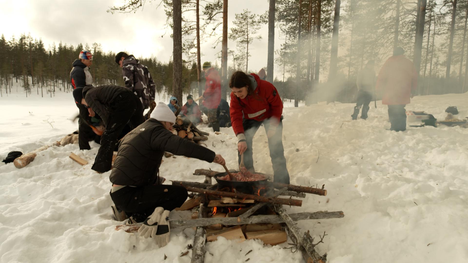 Junge Menschen bereiten auf einem Lagerfeuer Essen bei einer Übung im Freien zu. | ARD Stockholm