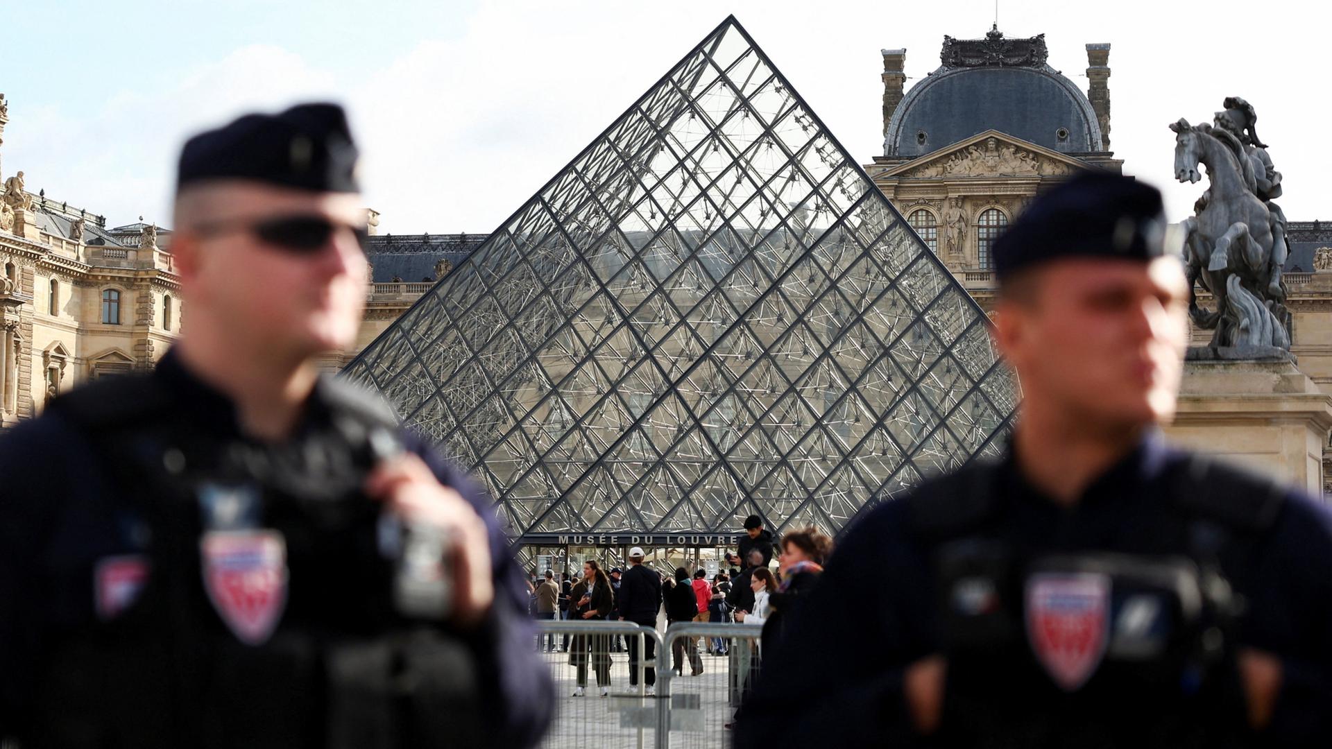 Zwei Polizisten stehen vor der Pyramide des Pariser Louvre. | REUTERS