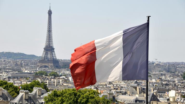 Die Flagge Frankreichs weht vor dem Eiffelturm in Paris.