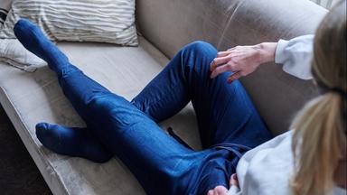 Eine Frau liegt in ihrer Wohnung auf einem Sofa.