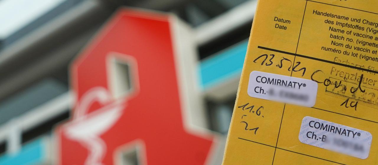 Ein Impfpass vor einer Apotheke