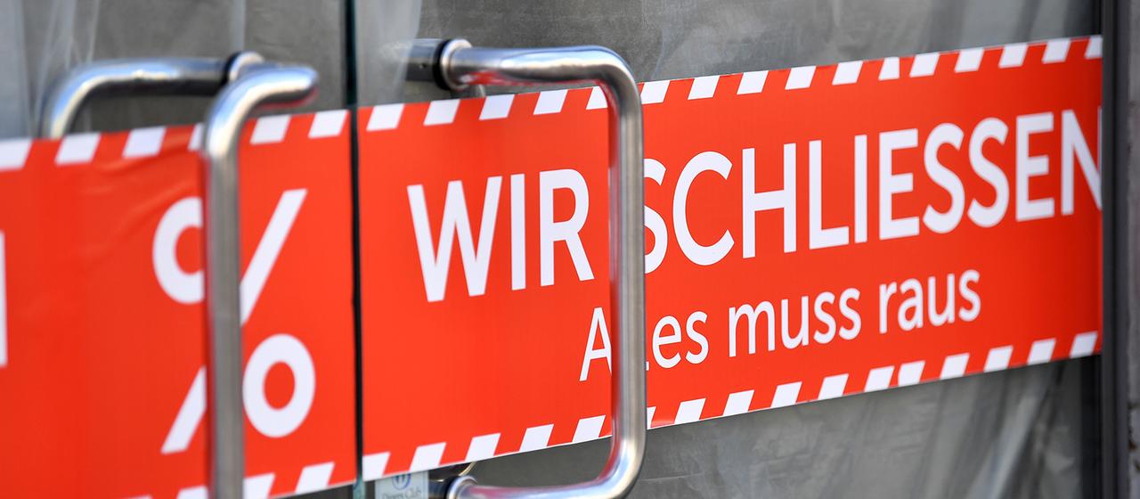 "WIR SCHLIESSEN Alles muss raus" steht auf dem Banner in der Tür eines Geschäfts.