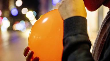 Ein Mann atmet Lachgas aus einem Luftballon ein.