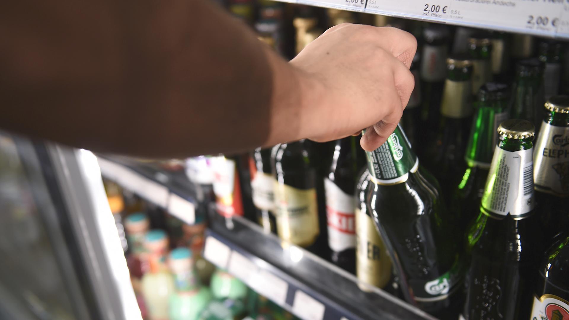 Ein Mann holt eine Flasche Bier aus einem Kühlschrank in einem Spätkauf, Berlin