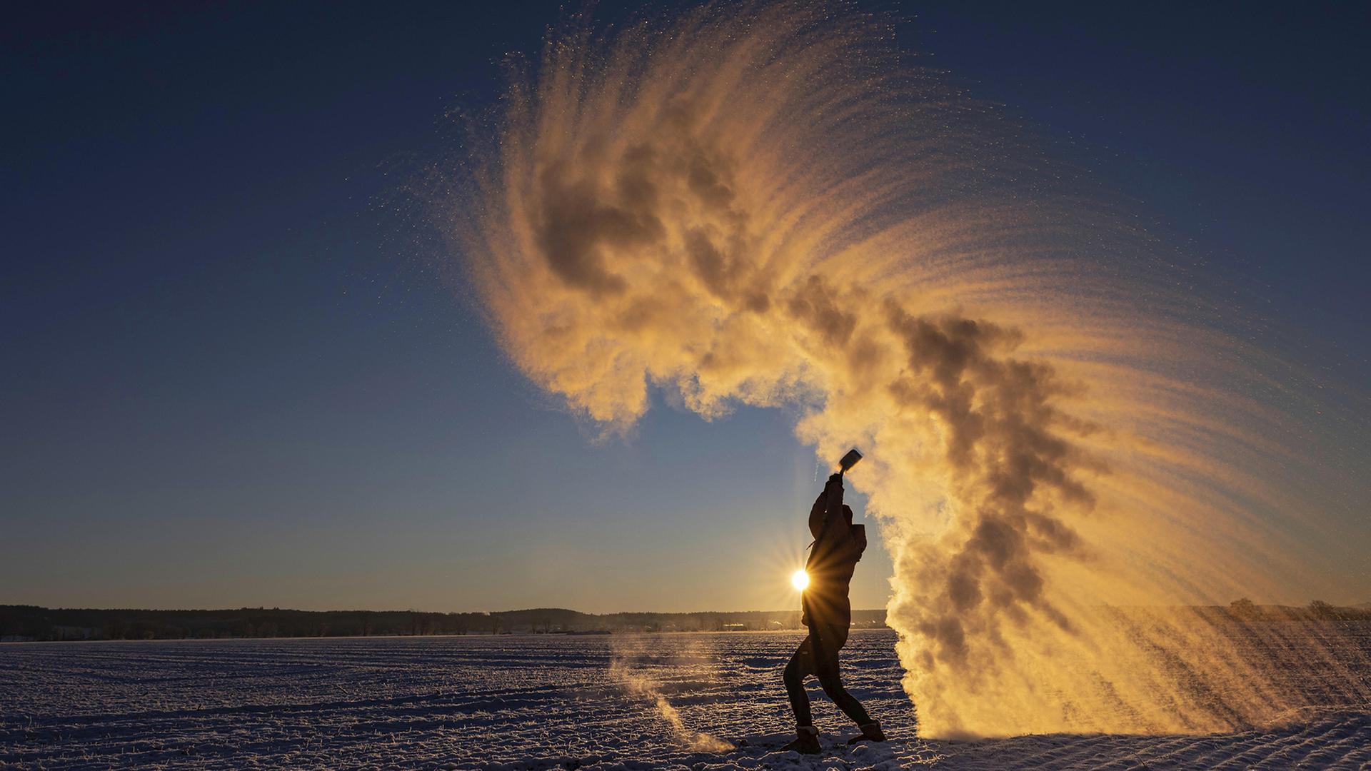 Frau wirft hei�es Wasser in die Luft, das zu Eiskristallen gefriert. | picture alliance / imageBROKER