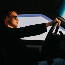  Eine junge Frau mit Sonnenbrille beim Autofahren.
