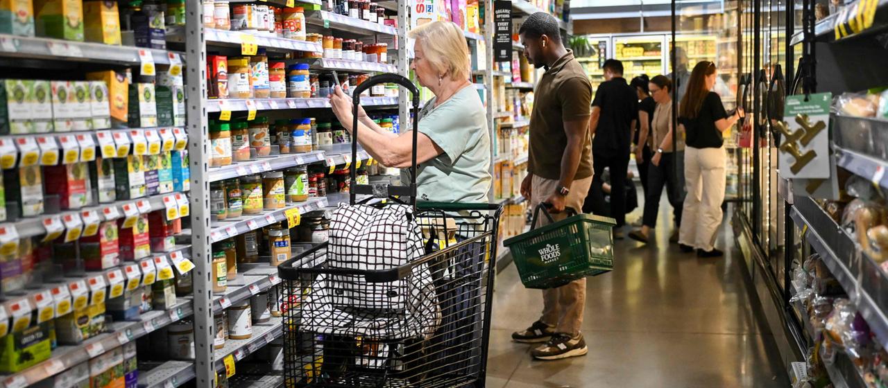 Menschen stehen in einem amerikanischen Supermarkt vor einem Regal
