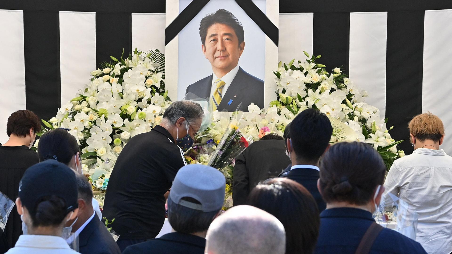 Ein Foto von Shinzo Abe steht inmitten von Blumen | AFP