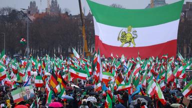 Menschen vor einer großen alten iranischen Staatsflagge
