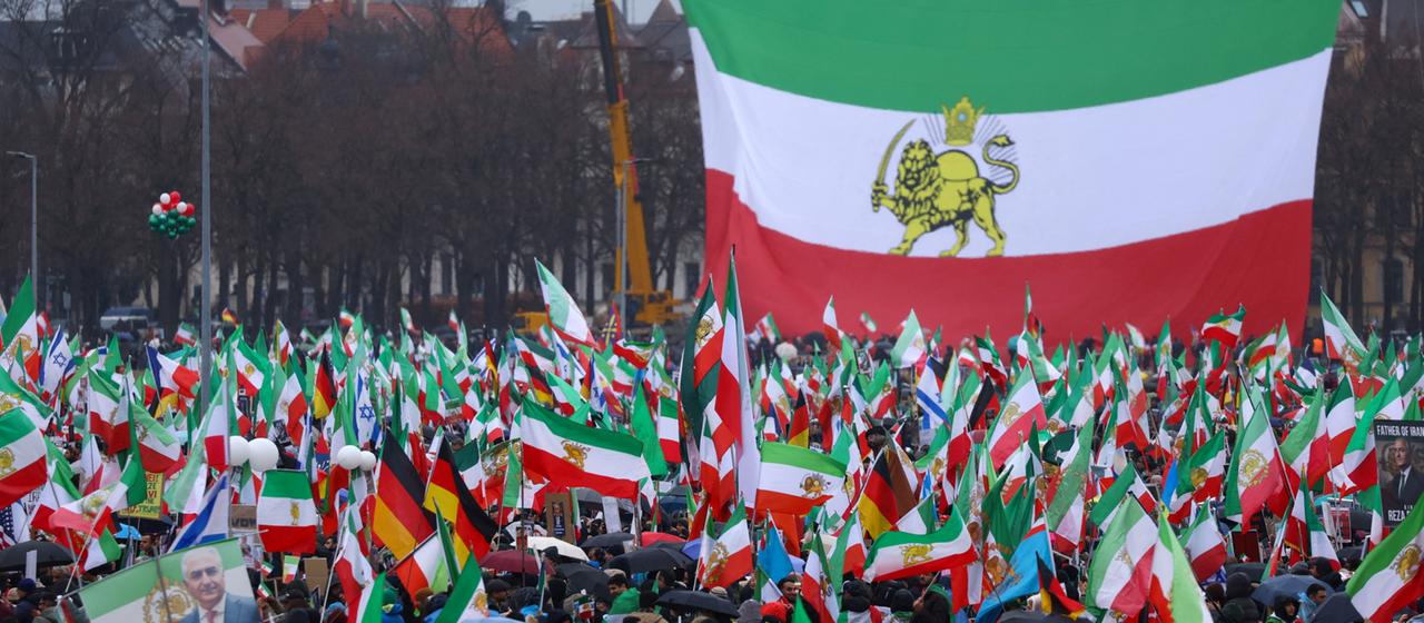 Menschen vor einer großen alten iranischen Staatsflagge