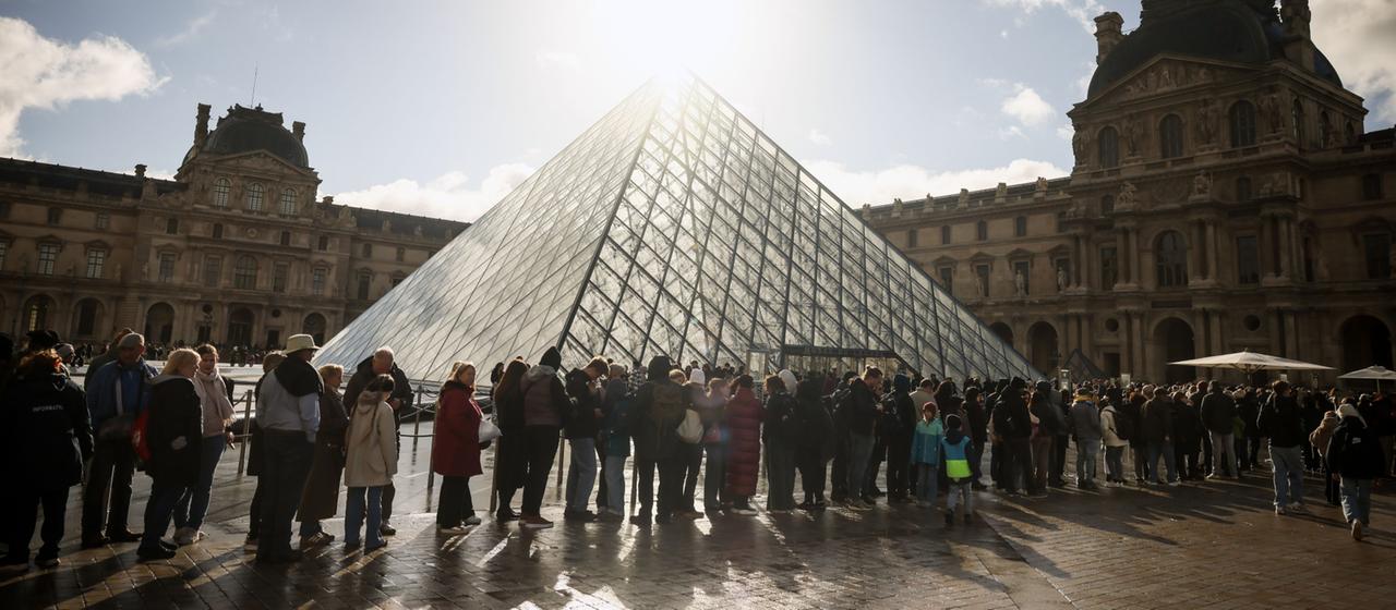 Visitors queue in front of the Louvre in Paris
