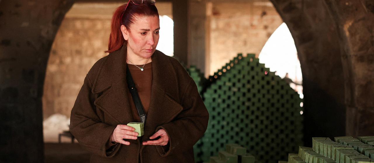 Aisha Zain Jbaily hält ein Stück Lorbeerseife in der Hand.