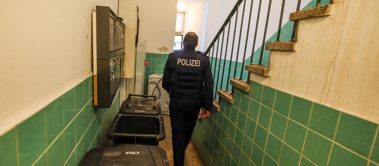 Ein Polizist geht durch ein Treppenhaus.