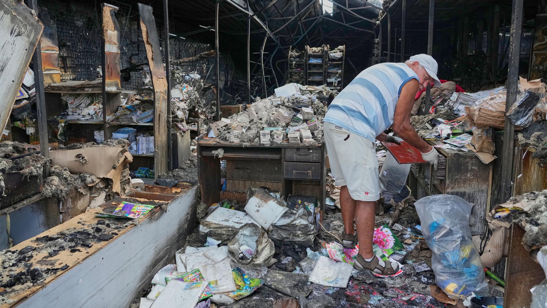 Ein Mann sucht nach unversehrten Büchern nach einem Brand auf dem Gelände des größten Buchmarkts der Ukraine in Kiew. | AP Photo/Efrem Lukatsky