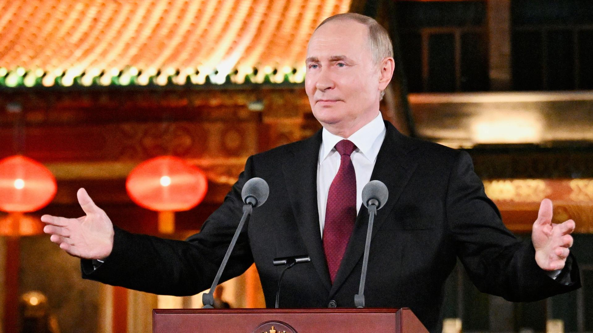 Wladimir Putin steht mit ausgebreiteten Armen an einem Rednerpult. | Sergei Bobylev/Pool Sputnik Krem