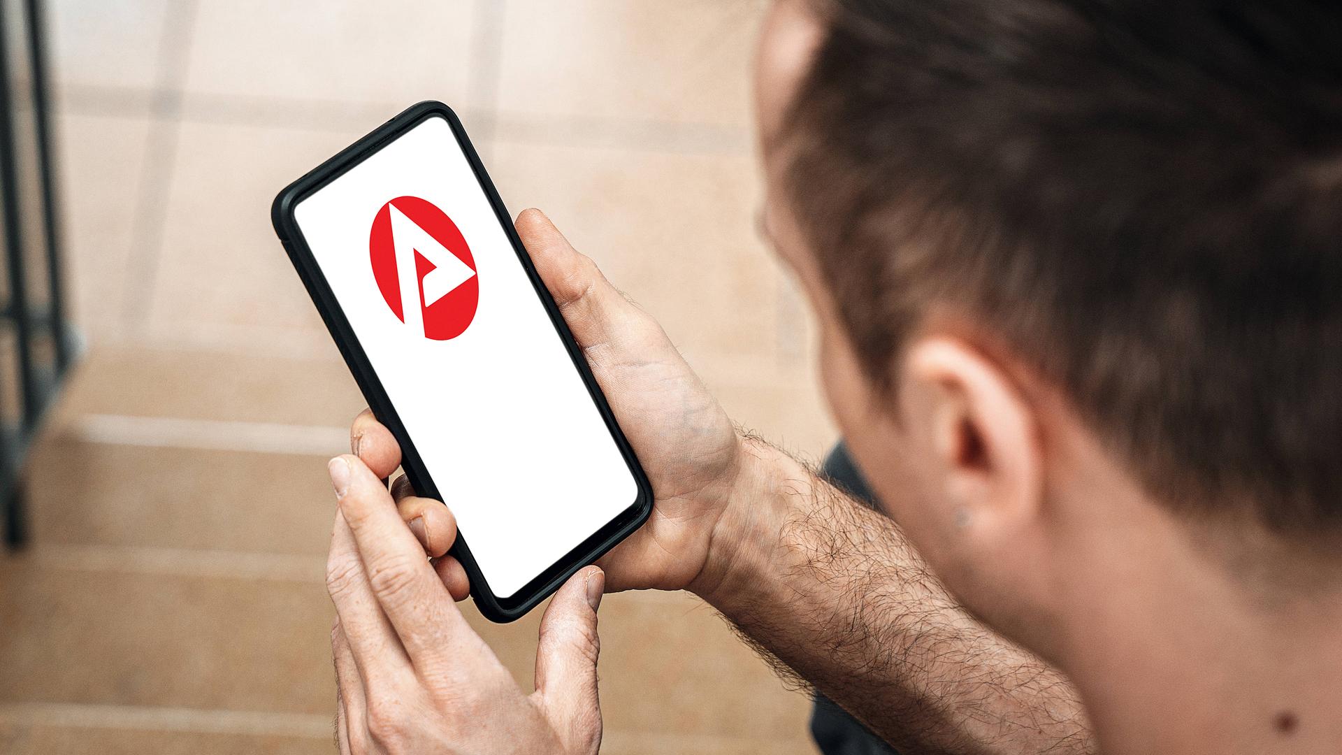 Ein Mann mit einem Smartphone in der Hand. Bundesagentur für Arbeit Website oder App auf dem Bildschirm.  | IMAGO/ Bihlmayerfotografie