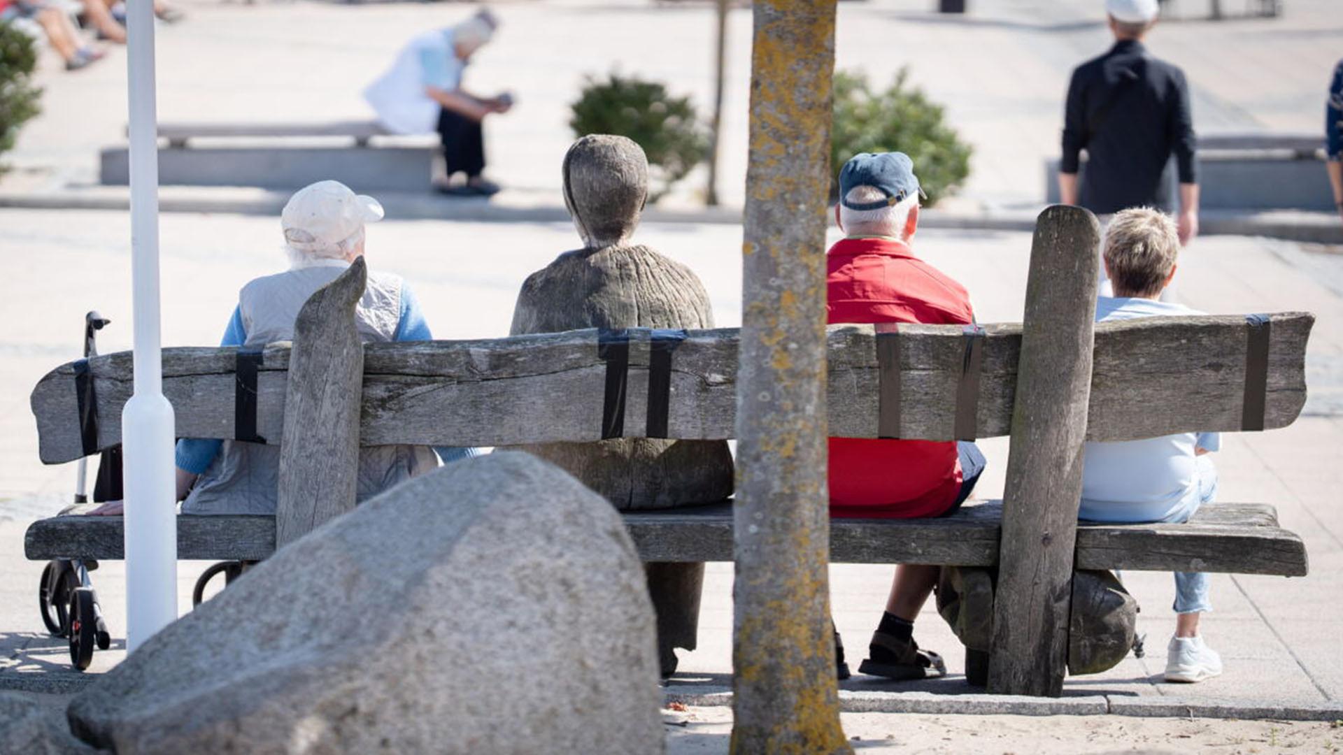 Ältere Menschen sitzen auf einer Bank in der Sonne. (Quelle: dpa/Janssen) | dpa/Janssen