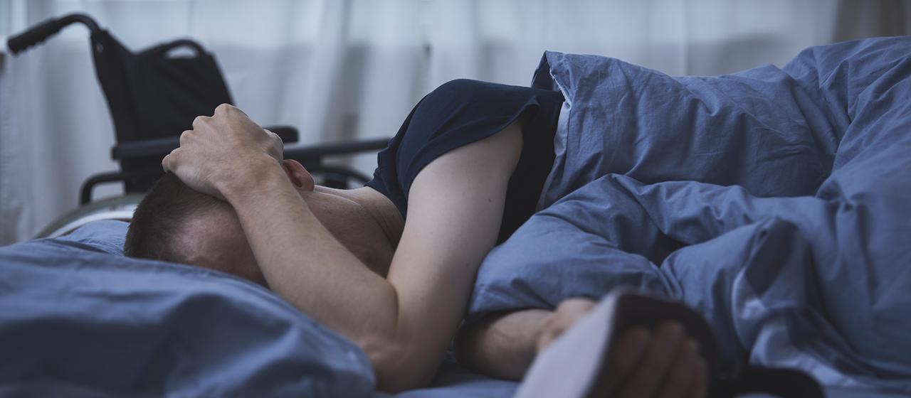 Ein Mann mit Long-Covid liegt in einem Bett.