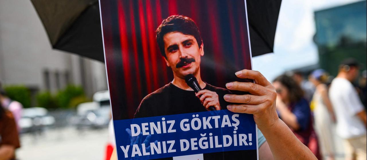 Ein türkischer Linker skandiert Parolen für den türkischen Komiker Deniz Goktas, der festgenommen und vor Gericht gebracht wurde, und hält dabei ein Banner mit der Aufschrift "Deniz Goktas nicht allein" vor dem Caglayan-Gericht am 3. Juli 2026.