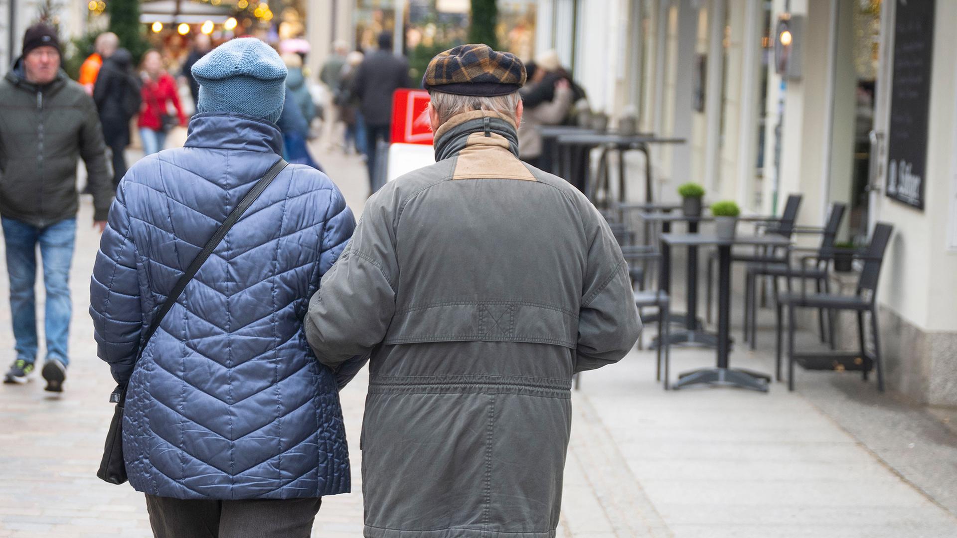 Ein älteres Paar geht Arm in Arm durch eine Einkaufsstraße in Schwerin. | dpa