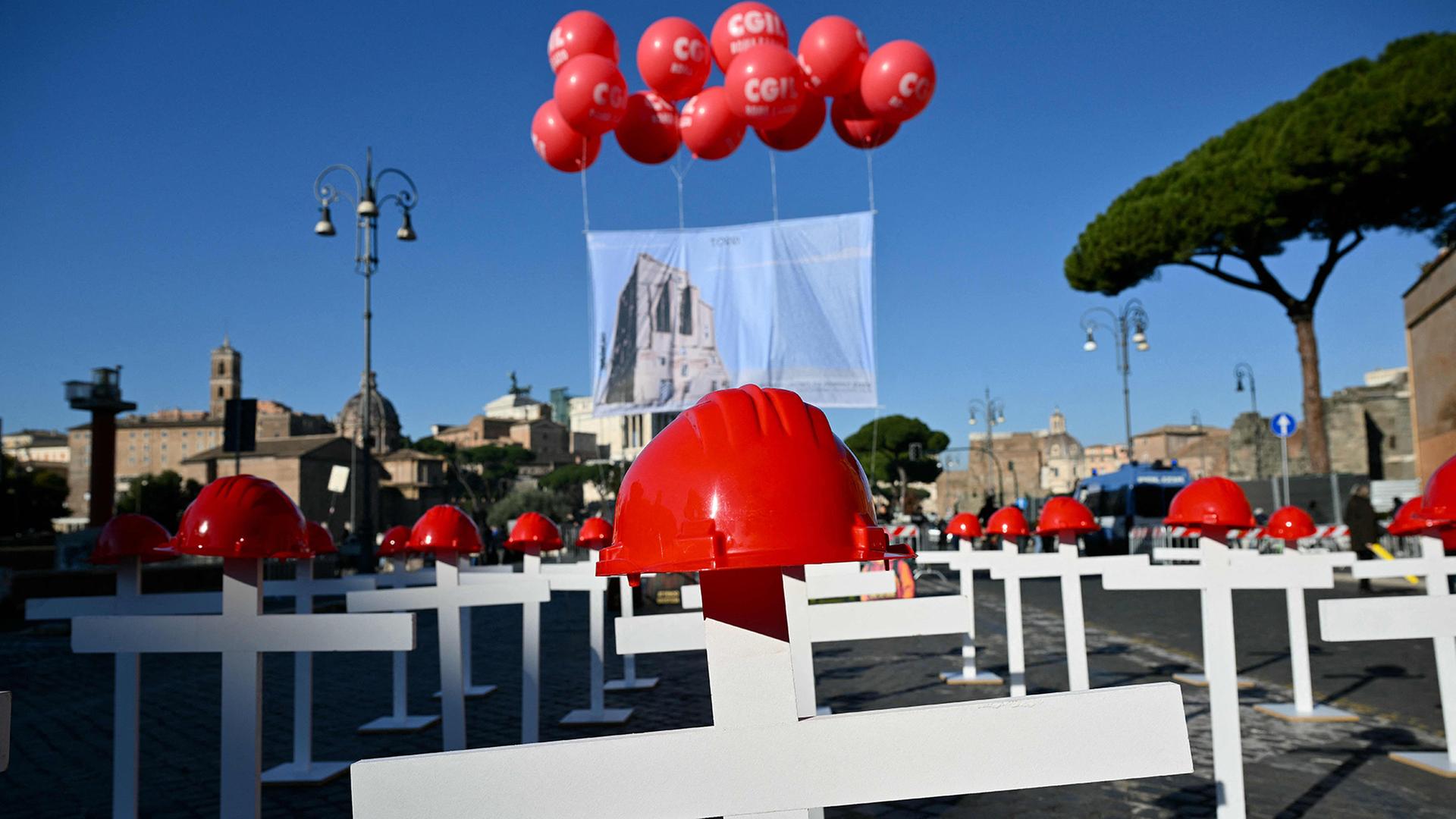 Eine Installation aus weißen Kreuzen mit roten Helmen erinnert an Todesfälle am Arbeitsplatz auf der Via del Foro Imperiale in Rom während eines landesweiten Streiktages | AFP