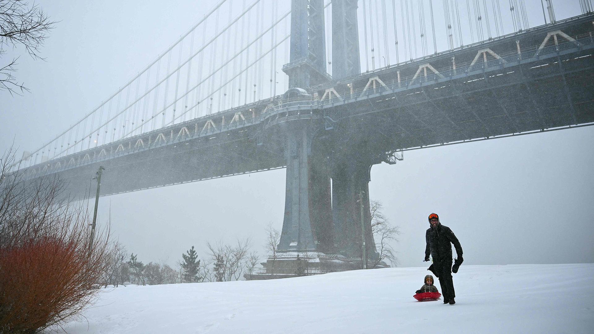 Ein Mann zieht in New York City ein Kind auf einem Schlitten. | AFP