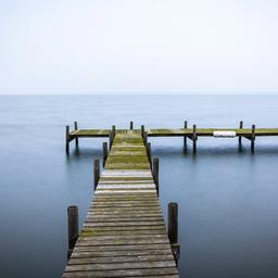  Ein Steg ragt am frühen Morgen bei trübem Wetter in das Steinhuder Meer in der Region Hannover. 