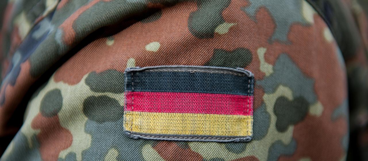 Die Deutschlandflagge ist auf der Uniform eines Soldaten zu sehen. | picture alliance / dpa Die Deutschlandflagge ist auf der Uniform eines Soldaten zu sehen.