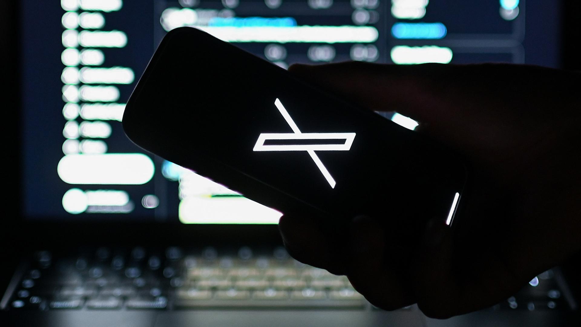 Das Logo des Kurznachrichtendiensts X ist auf einem Smartphone zu sehen, das vor die Webversion von X gehalten wird.  | dpa