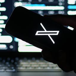 Das Logo des Kurznachrichtendiensts X ist auf einem Smartphone zu sehen, das vor die Webversion von X gehalten wird. 