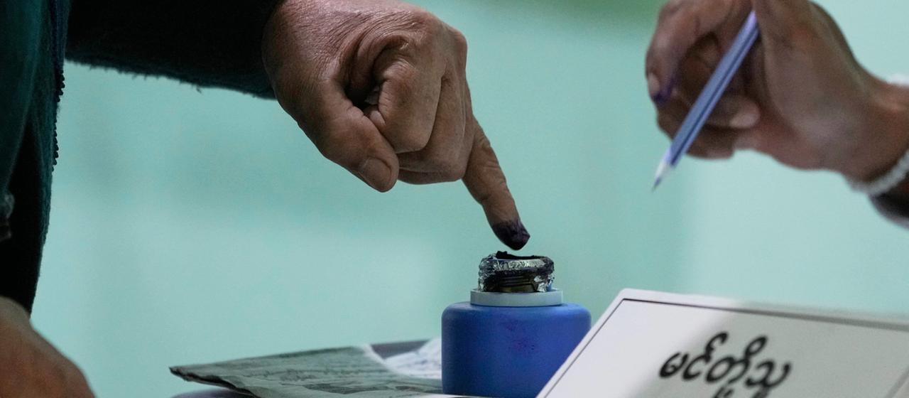 Ein Mann tippt seinen Finger in ein blaues Tintenfass